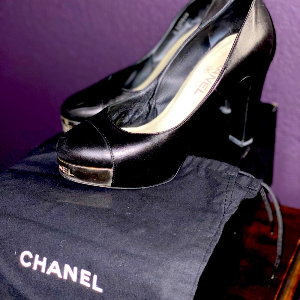Chanel, Gently used, black pumps with silver, engraved “Chanel” on the toe.